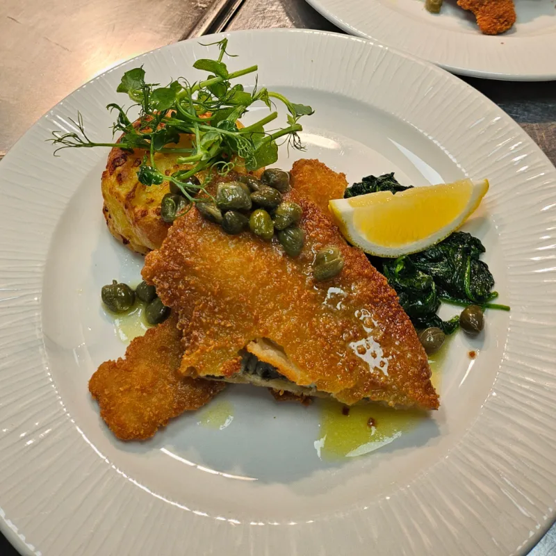 Breaded plaice, Wilted spinach, Dauphinoise potatoes, Caper butter sauce, Lemon segment